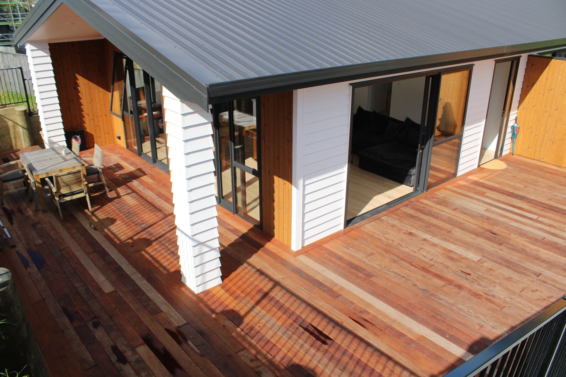 Covered timber deck with outdoor chairs and open sliding doors