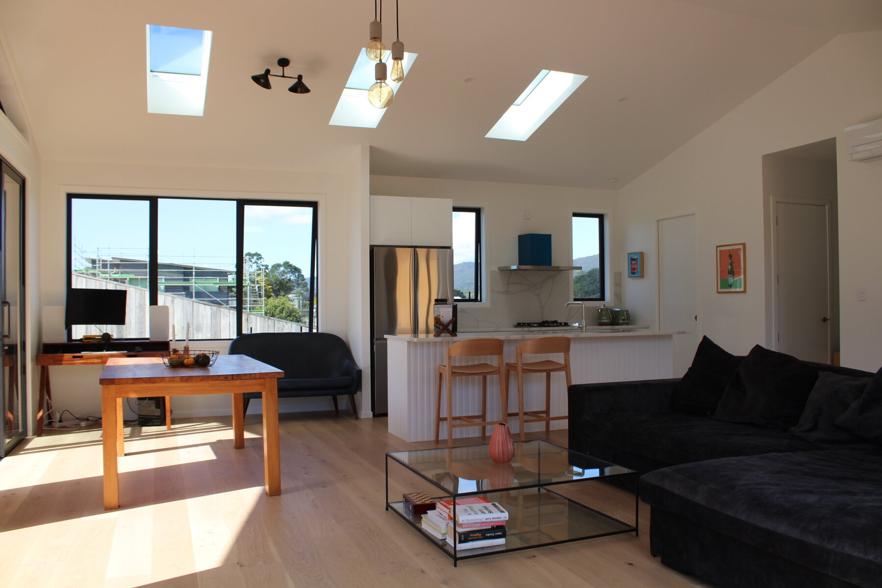 Bright lounge with skylights, dining table, and black sofa
