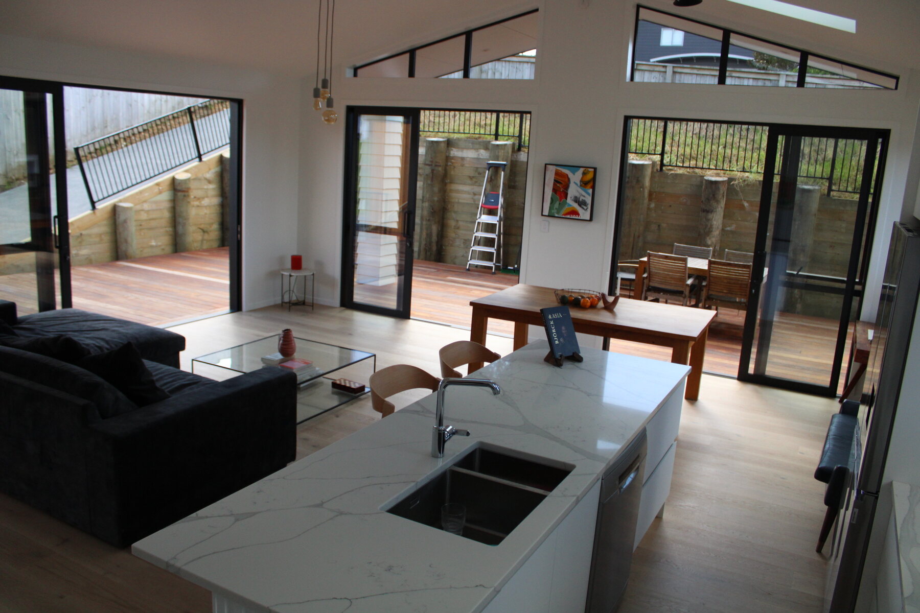 Kitchen island and living area with open doors to the deck