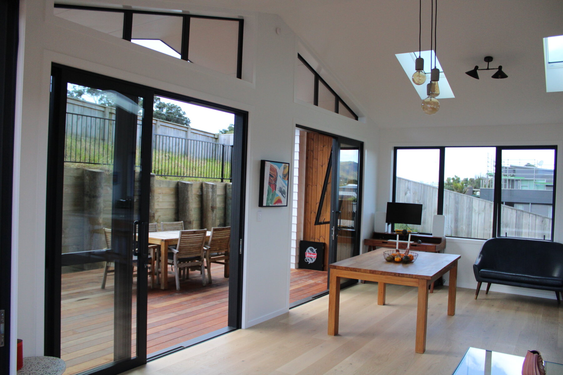 Living room with black sofa, glass coffee table, and deck access